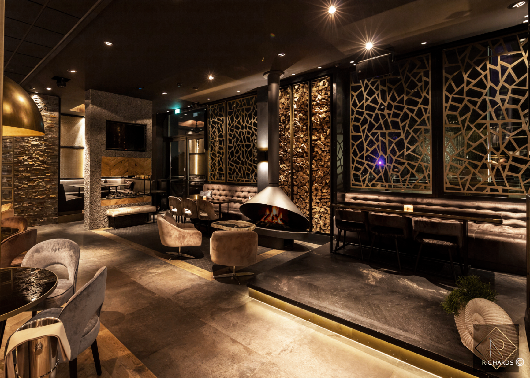 Ammonite hospitality interior — sculptural fireplace and laser-cut screens